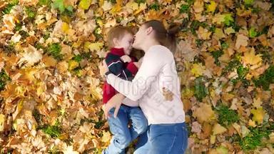 4k视频：小学步男孩与母亲玩耍，互相挠痒痒，拥抱和亲吻，而躺在黄色